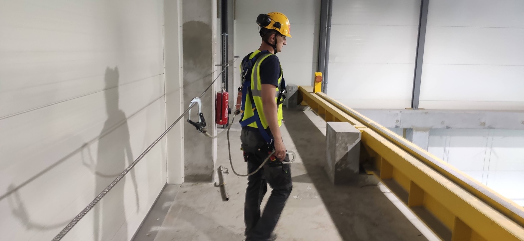 Pracownik zabezpieczony systemem ROLER500 podczas pracy przy krawędzi podestu
